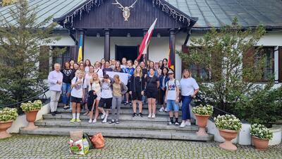 Die Jugendlichen der Jugendbegegnung stehen vor einem Haus und l&auml;cheln in die Kamera.