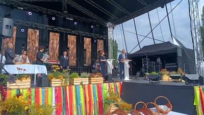 Sechs Personen stehen auf einer anl&auml;sslich des Erntedankfests geschm&uuml;ckten B&uuml;hne.