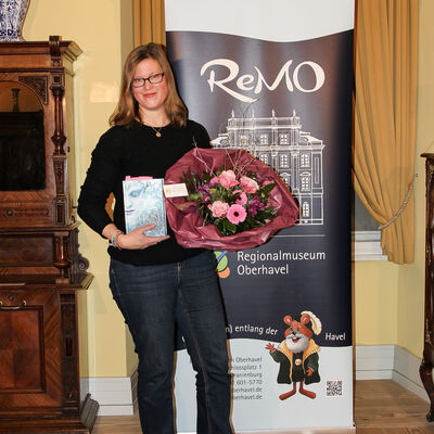 Anna Fleck mit ihrem Buch und einem Strau&szlig; Blumen in der Hand