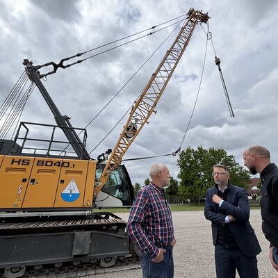 Drei M&auml;nner stehen vor einer Planierraupe mit dem Aufdruck HS 8040.