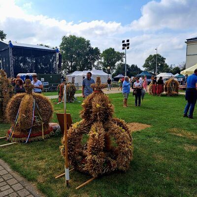 Eine B&uuml;hne und eine geschm&uuml;ckte Festwiese mit Sonnenschirmen und vereinzelten Menschen im Hintergrund.