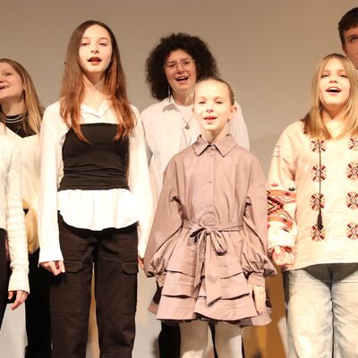 Jungen und M&auml;dchen im Chor auf einer B&uuml;hne.