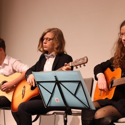 Drei Jungen mit Gitarren auf einer B&uuml;hne.