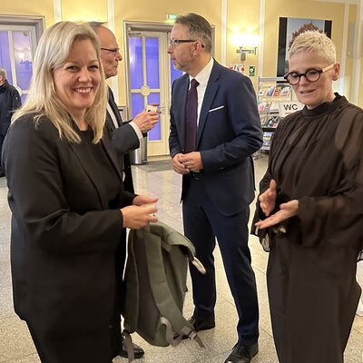 M&auml;nner und eine Frau auf einem Stehempfang bei einer Begr&uuml;&szlig;ung.