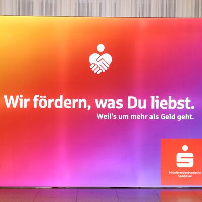 Ein Banner mit buntem Farbverlauf und der Aufschrift: Wir f&ouml;rdern, was du liebst. Absender ist die Mittelbrandenburgische Sparkasse (MBS).