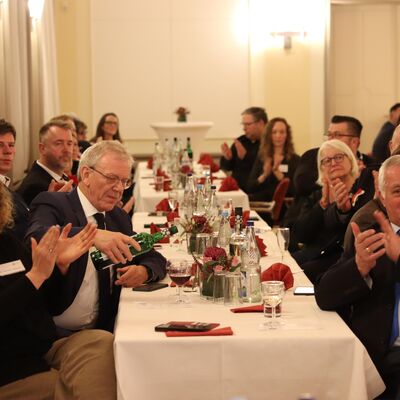 Menschen sitzen an einer gedeckten Festtafel.