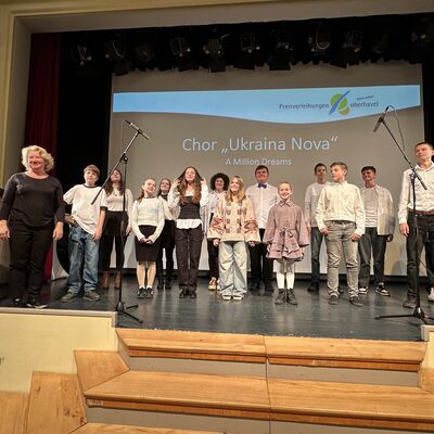 Jungen und M&auml;dchen im Chor auf einer B&uuml;hne.