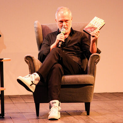 Marc Raabe sitzt in einem Sessel auf der B&uuml;hne im gro&szlig;en Saal der KulturFuge und erz&auml;hlt &uuml;ber dein Buch.