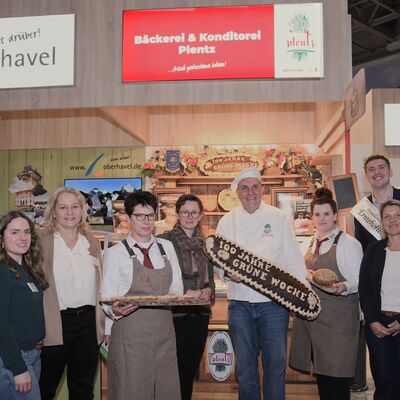 Eine Gruppe von Frauen und M&auml;nnern stehen vor einem Messestand auf der Gr&uuml;nen Woche.