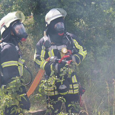 Zwei Kameraden der Feuerwehr, stehend im B&ouml;schungsbereich des Gleises, nahe dem Verunfalltem Zug, bei leichter Rauchentwicklung. Eine aktive Brandbek&auml;mpfung war aufgrund nicht freigegebener Bahnstrecke zu diesem Zeitpunkt noch nicht m&ouml;glich.